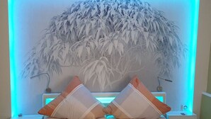 Une chambre à coucher avec un lit, deux tables de chevet et une lampe fixée au mur.
