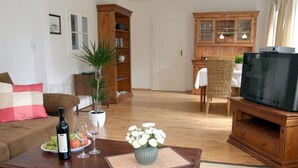 Un salon avec une table basse en bois, un canapé, un téléviseur, un meuble et une plante en pot.