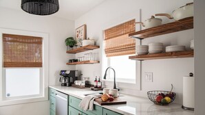 A kitchen with teal cabinets, wooden shelves, a coffee machine, and a fruit bowl. - Brick Haven House: King Suite, Near SUU, EV Charger, Parking, Nat’l Parks (Cedar City)