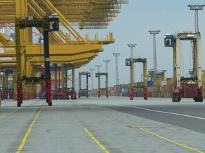 A cargo handling area with yellow gantries, red machinery, and shipping containers. - Holiday Home Hermann (Butjadingen)
