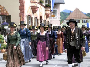 Eine Gruppe von Menschen in traditioneller Kleidung geht vor einem Gebäude mit aufwendiger Architektur und einem Schild, auf dem 'Museum' steht.
