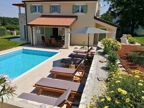 Una piscina con sillas de descanso y un patio con mesa y sillas.