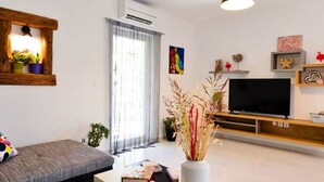 A modern living room with a sofa, a TV, a coffee table with books, and decorative plants. - Villa Stella Comfortable Holiday Residence (Umag)