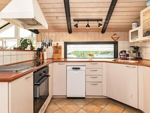 Una cocina moderna con armarios de madera, lavavajillas y ventana con vistas a la vegetación.