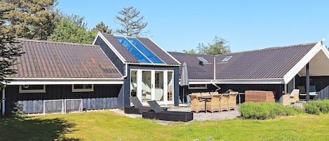 A residential property with a sloped roof, a covered patio area, and a fenced yard.