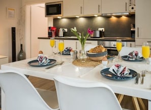 A modern kitchen with a dining table set for breakfast, including plates, cutlery, and a vase with flowers. - Holiday With Beach Chair (Groemitz)