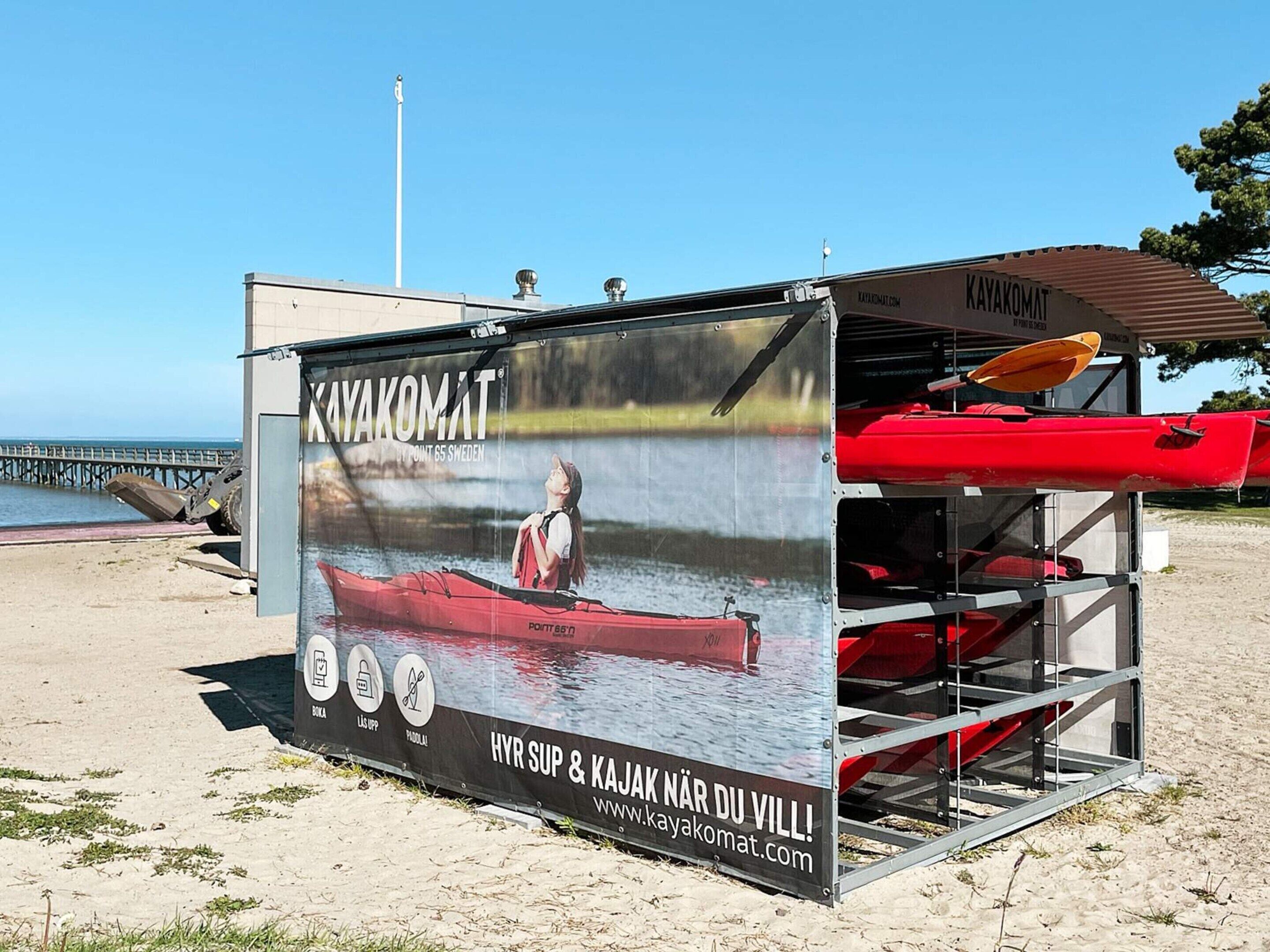 A kayak rental kiosk with a large advertisement featuring a woman kayaking.