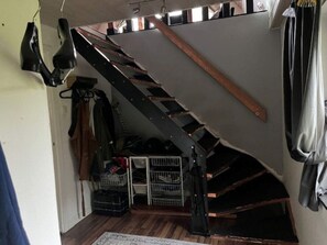 A narrow staircase with a wooden handrail and metal steps, leading to a lower level.