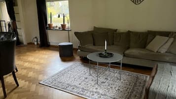 A living room with a sofa, a coffee table, a rug, and a Harley-Davidson logo on the wall.