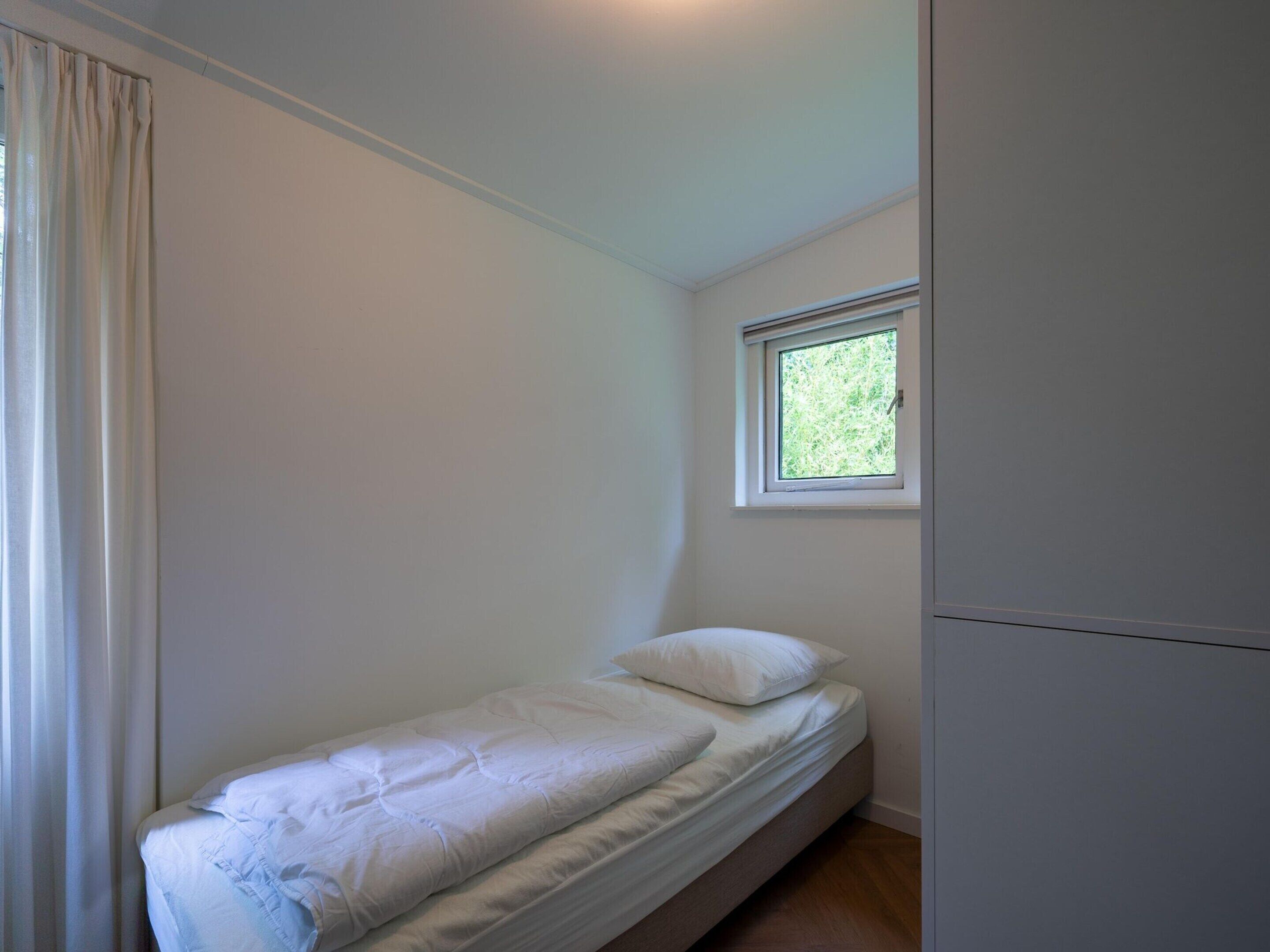 A small, single-bed room with a window providing natural light.