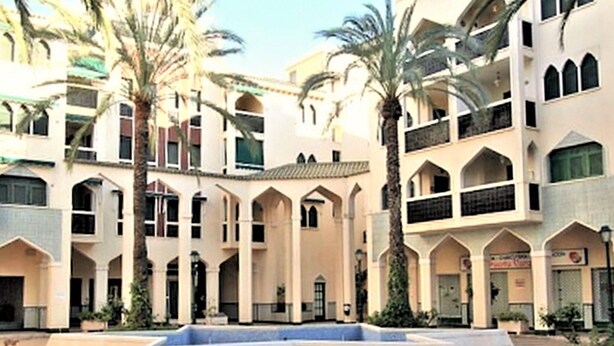 A multi-story building with a central courtyard, palm trees, and a fountain. - Belvilla by OYO Apartment in Santa Pola (Santa Pola)