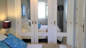 A bedroom with a double bed, a wardrobe with mirrored doors, and a bedside table with a lamp. - Belvilla by OYO Apartment in Santa Pola (Santa Pola)