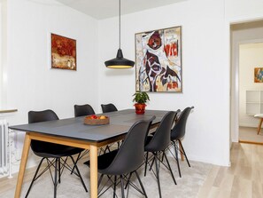 A dining area with a rectangular table, black chairs, a potted plant, and two abstract paintings on the walls. - 6 Person Holiday Home in Skals (Skals)