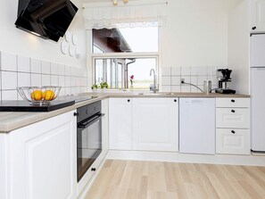 A modern kitchen with white cabinetry, a built-in oven, a dishwasher, and a window with a view. - 6 Person Holiday Home in Skals (Skals)