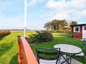 A patio with a table and chairs, a small shed, and a view of the sea.