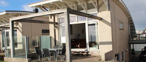 A modern house with a covered patio, large windows, and a brick exterior.