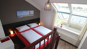 A bedroom with a bed, a nightstand, a lamp, a painting, and a window with a view of a body of water. - Dijkvilla on the Ijsselmeer (Makkum)