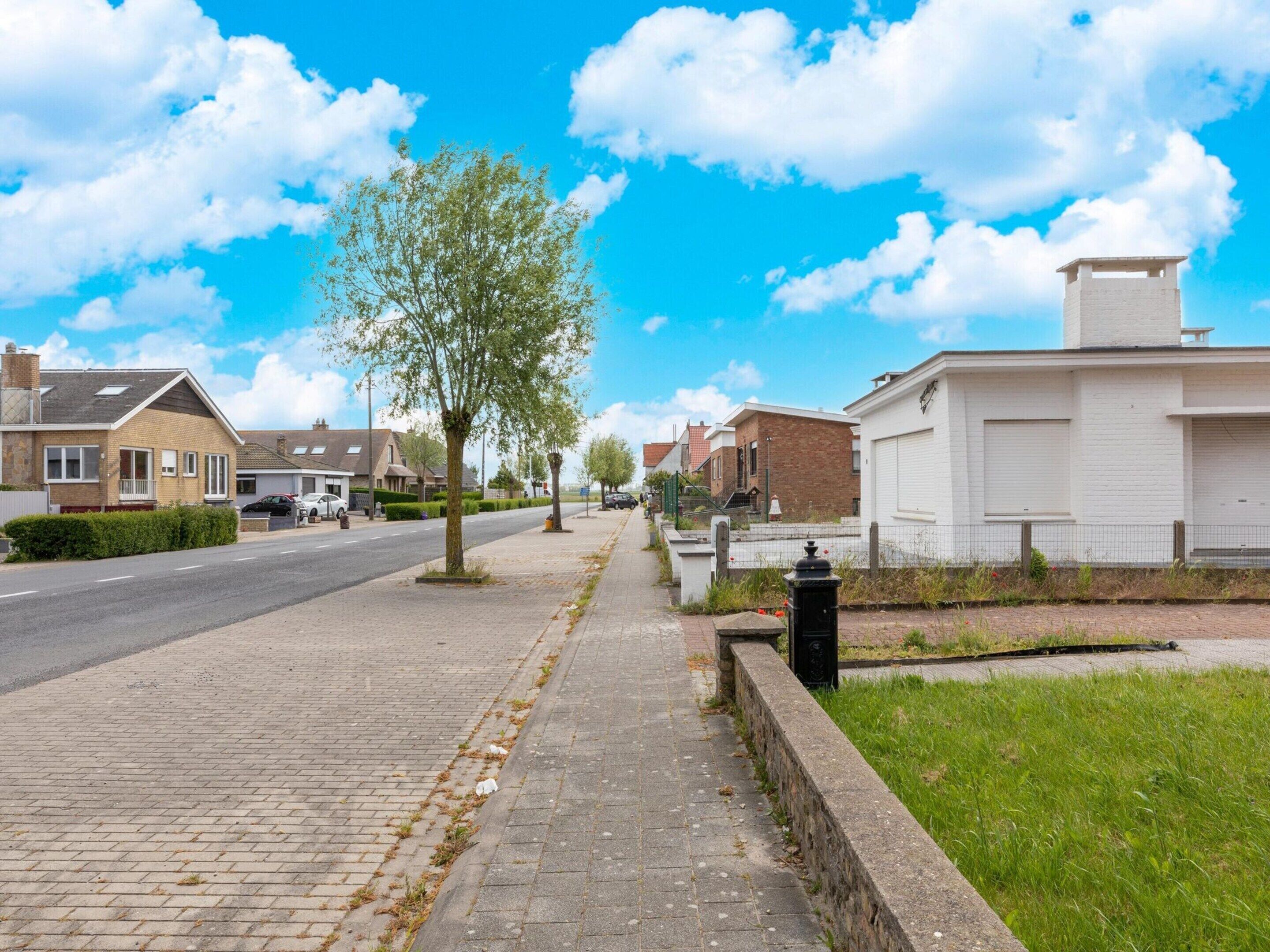 Una calle residencial con casas, aceras y cielo despejado.