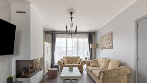 A living room with a sofa set, a coffee table, a fireplace, and a television. - Modern Villa w/ Private Yard (Middelkerke)