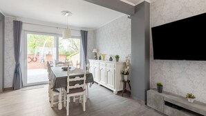 A modern living room with a dining area, a fireplace, and a TV mounted on the wall. - Modern Villa w/ Private Yard (Middelkerke)