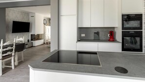 A modern kitchen with a central island, built-in appliances, and a dining area with a bench. - Modern Villa w/ Private Yard (Middelkerke)