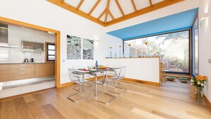 Una cocina moderna con armarios de madera, una mesa de comedor de cristal y un ventanal amplio.