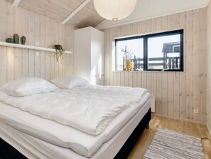 A bedroom with a bed, a window with a view, and wooden walls. - 5 Star Holiday Home in Hirtshals (Hirtshals)