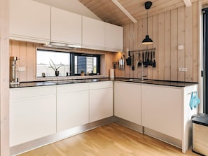 A modern kitchen with wooden walls, a black countertop, and a window. - 5 Star Holiday Home in Hirtshals (Hirtshals)