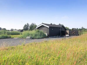 A rustic building with a sloped roof, a wooden door, and a small porch area.