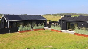 A modern building with a flat roof, large windows, and a grassy yard with plants. - 5 Star Holiday Home in Hirtshals (Hirtshals)
