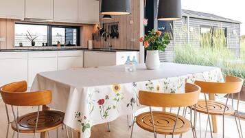 A modern kitchen with white cabinets, a dining table with a floral tablecloth, and a view of the outside.