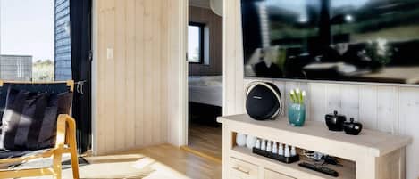 Una sala de estar moderna con un televisor de pantalla plana grande, piso de madera, un sofá y una mesita de centro.