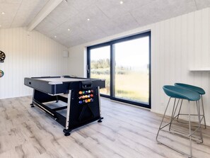 A pool table with a ball rack, a dartboard, and two bar stools in a room with a large window. - 5 Star Holiday Home in Hirtshals (Hirtshals)