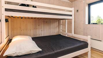 A bunk bed with a black mattress and white pillow, wooden walls, and a window with a view.