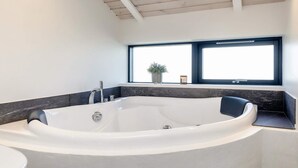 A modern bathroom with a freestanding bathtub, a toilet, and a window providing a view. - 5 Star Holiday Home in Hirtshals (Hirtshals)