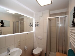 Ein modernes Badezimmer mit großem Spiegel, Dusche und Toilette.