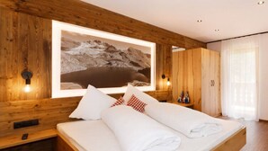A wooden room with a bed, a large framed picture, and wooden cabinets. - Holiday Home Hutterwirtshof (Moso in Passiria)