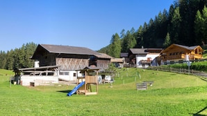 A rural village with traditional wooden houses, a playground, and a clear blue sky. - Holiday Home Hutterwirtshof (Moso in Passiria)