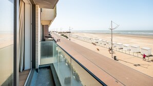 A balcony with a view of a beach and promenade.