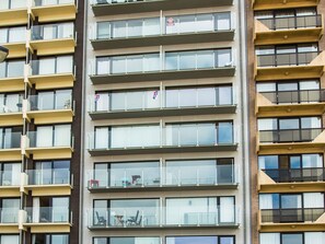 Een meerhoog gebouw met balkons, grote ramen en een bakstenen gevel.