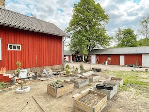 A red barn with a dirt yard and raised garden beds. - 4 Person Holiday Home in Furuby (Hovmantorp)