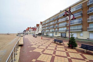 Ein Strandhotel mit mehreren Balkonen, einem Schachbrettmuster-Gehwegen und einer kleinen Weihnachtstanne.