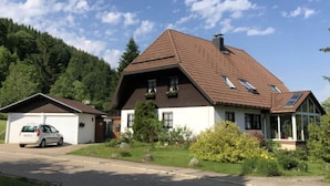 A two-story house with a sloped roof, a garage, and a front porch with a glass door. - Kassler Comfortable Holiday Residence (Feldberg)