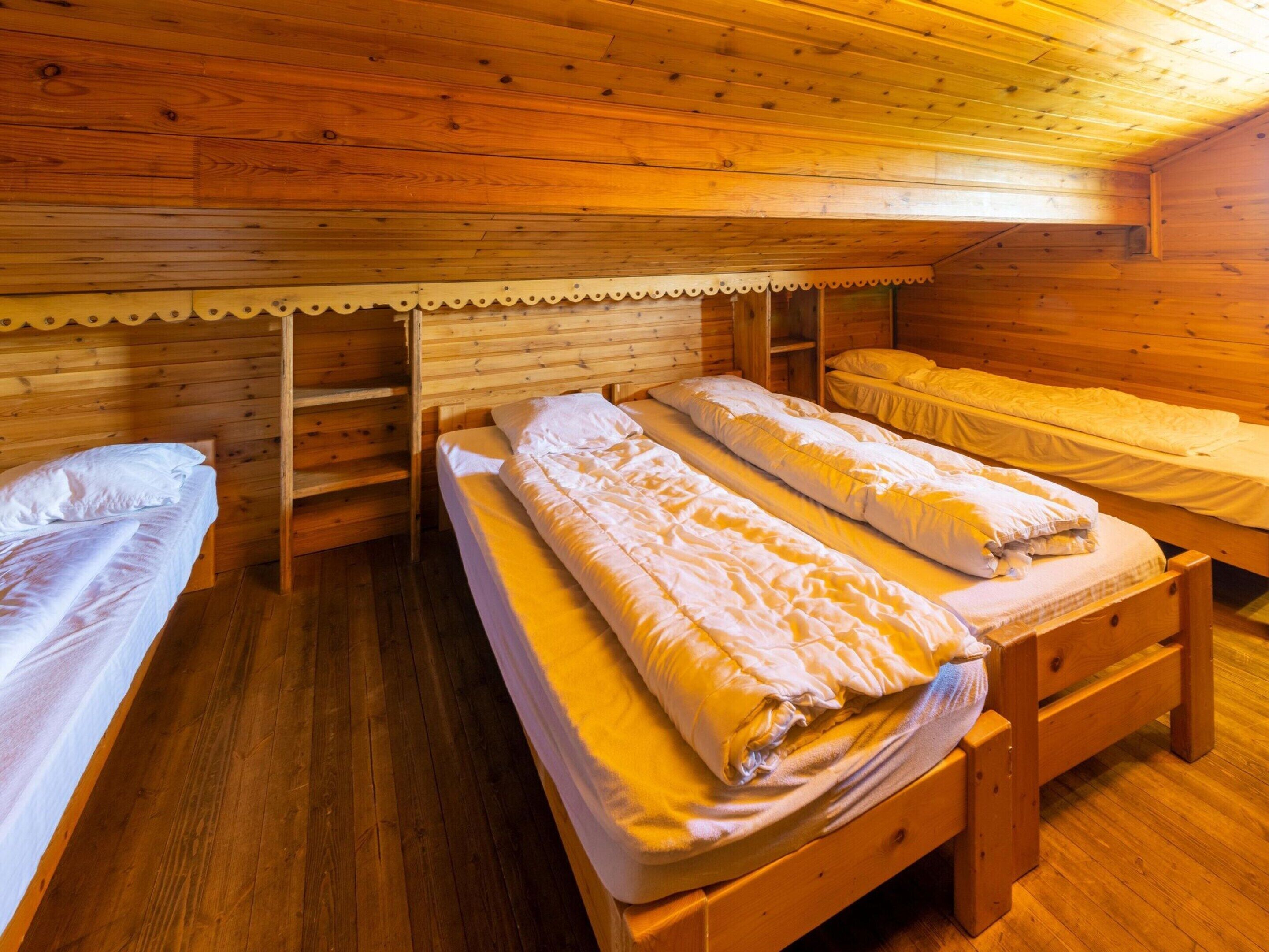 A cabin with three wooden beds arranged in a row, each with a mattress and pillows.
