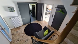 Un interior moderno con una escalera, un comedor con mesa y sillas redondas, y vistas de la cocina contigua y el espacio exterior.