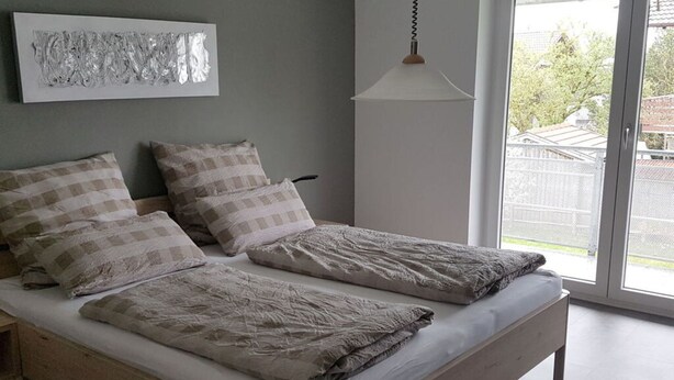 Una cama doble con estructura de madera, dos almohadas y una manta.