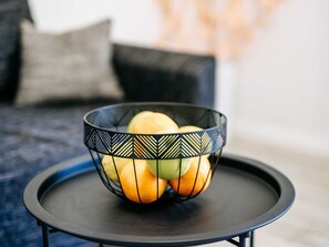 Una cesta de mimbre negra con frutas sobre una pequeña mesa negra.