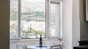 Un comedor con una mesa y sillas, una botella de vino y un florero con flores.