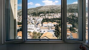 Una habitación con un ventanal grande que da a una vista de un pueblo con edificios y una colina.
