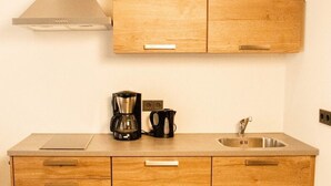 Una cocina con armarios de madera, un lavamanos de acero inoxidable y una cafetera.